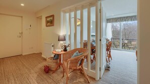 A spacious room with a large sliding glass door leading to a balcony, wicker furniture, a lamp, and a radiator.