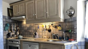Eine Küche mit Holzschränken, einer Edelstahl-Spüle und verschiedenen Küchenutensilien, die an der Wand hängen.