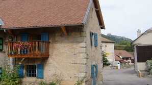 Ein Steinhaus mit Balkon, rotem Ziegeldach und blauen Fensterläden.