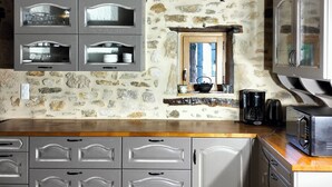 A rustic kitchen with stone walls, wooden beams, and grey cabinetry. - Gîte des 3 pays, ideal for reunions with family or friends (cublac)