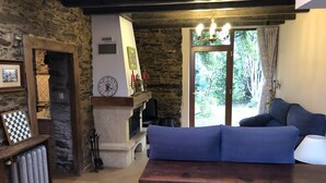 Un soggiorno accogliente con parete in pietra, camino, orologio e divano blu.