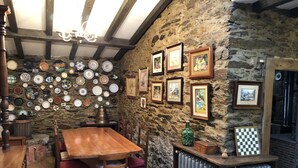 Un'area pranzo rustica con una parete in pietra decorata con piatti vari e opere d'arte incorniciate.
