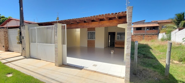 A residential property with a gated entrance, a covered patio, and a visible dog inside.