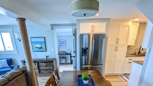 Una cucina moderna con tavolo da pranzo in legno, pensili bianchi e frigorifero in acciaio inossidabile.