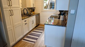 Una cucina moderna con mobili bianchi, un piano di lavoro in granito e un pavimento in legno.