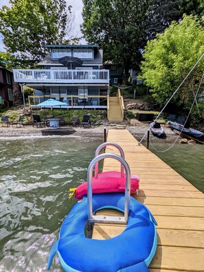 Un muelle de madera con una balsa inflable azul y un cojín rosa.