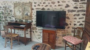Ein Wohnzimmer mit Fernseher, Holzmöbeln, einer Wandkarte und einer Wand mit Steinmuster.