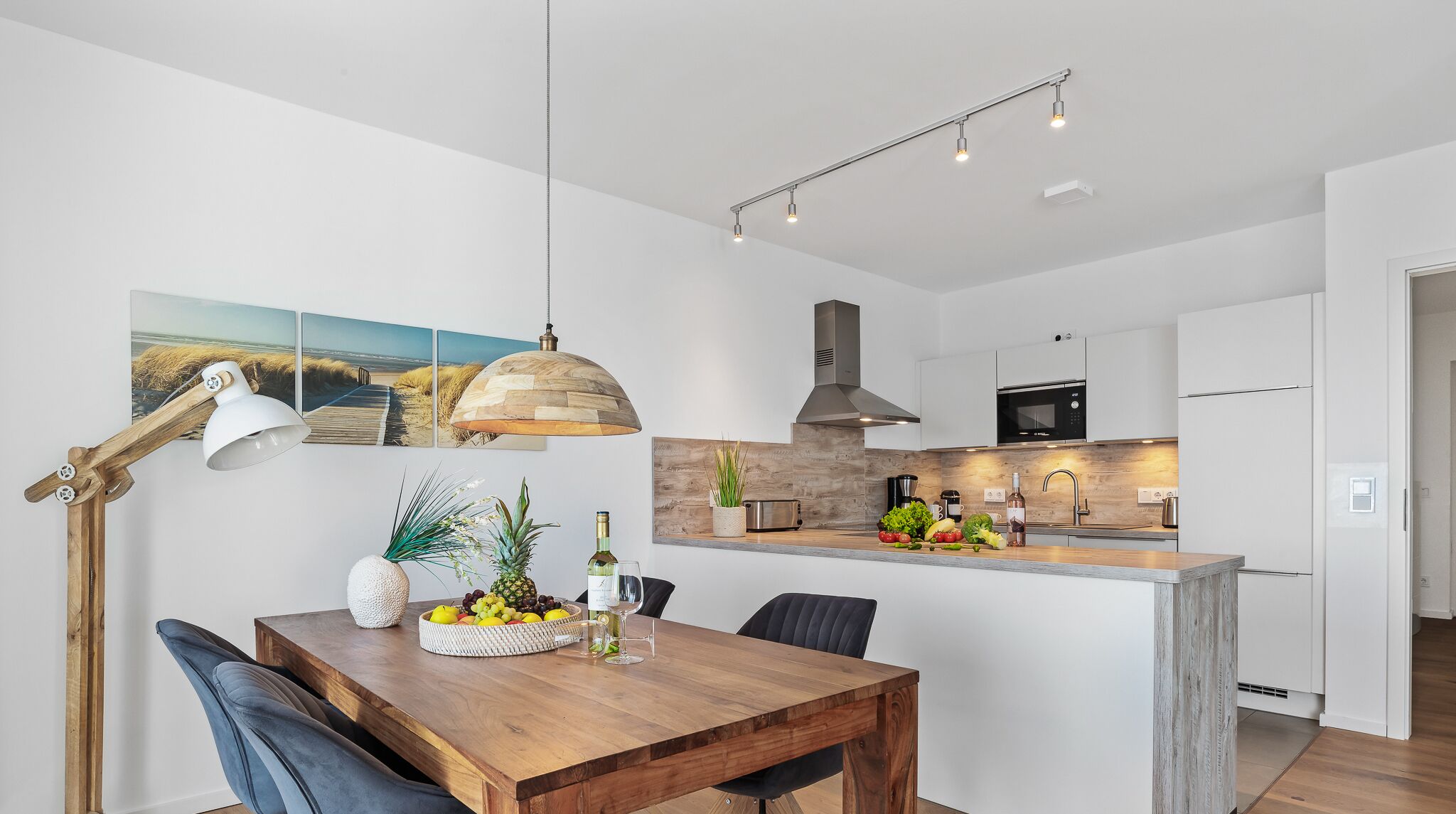 Eine moderne Küche mit weißen Schränken, einer Holztischinsel und einem Essbereich mit Holztisch und Stühlen.