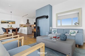 Uma sala de estar moderna com sofá cinza, mesa de centro de madeira e parede azul como destaque.