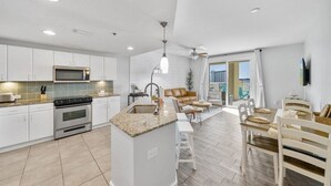 Una cocina moderna con armarios blancos, microondas integrado y una isla de encimera de granito.