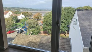Udsigt fra et vindue over et boligområde med huse, parkerede biler og en legeplads.