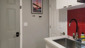 A kitchen with a white countertop, a black faucet, and a red backsplash. - Modern Luxury Oasis Near San Francisco/Oakland (Hayward)