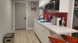 A modern kitchen with white cabinets, a stainless steel sink, and a red backsplash. - Modern Luxury Oasis Near San Francisco/Oakland (Hayward)