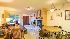 A cozy living room with a sofa, chairs, a fireplace, and a dining table. - Cozy Ski-in/Walk-out condo, free wifi, & parking, great deck (Copper Mountain)