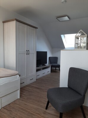 Relax in this stylish room with a large wardrobe, flat-screen TV, and comfortable armchair.