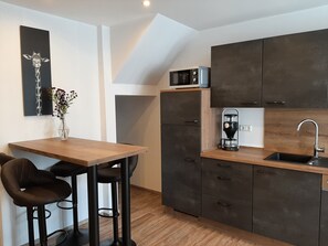 Enjoy cooking in this kitchen with a sink, coffee maker, and microwave, and dine at the wooden dining table with two bar stools.