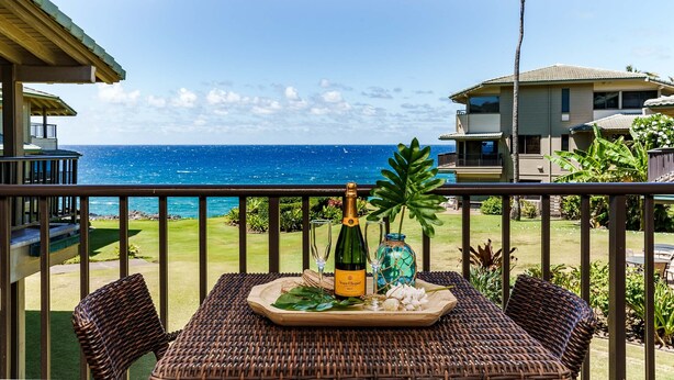 En balkon med havudsigt, en champagneflaske og et fad med et glas og en dekorativ genstand.