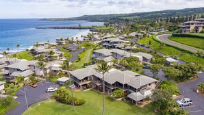 Kystresort med flere huse i bungalowstil, parkeringsplads og udsigt over havet.