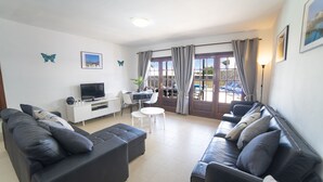 Ein modernes Wohnzimmer mit zwei Sofas, einem Fernseher und einem Essbereich mit Tisch und Stühlen.