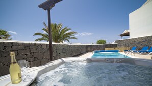 Ein Whirlpool mit Steinwand und Palmen im Hintergrund.