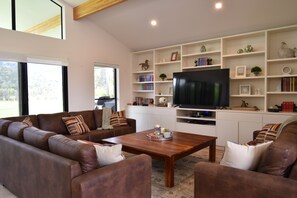A modern living room with a brown leather sofa set, a wooden coffee table, and a flat-screen TV on a white entertainment unit.
