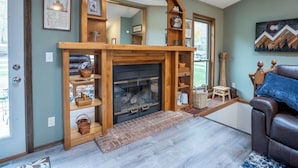 A cozy living room with a fireplace, wooden shelves, and a leather sofa.