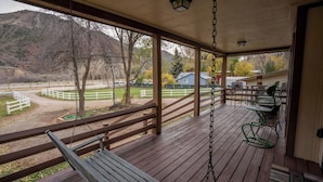 A covered porch with a swing, a table, and chairs.
