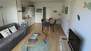 Olohuone, jossa on sohva, sohvapöytä, televisio sekä ruokailutila, jossa on tuoleja ja pöytä.