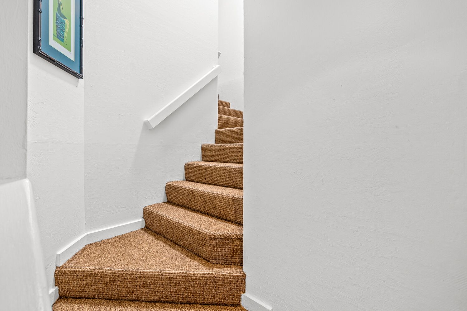 A staircase with a textured carpet and white walls.