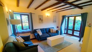 A living room with two sofas, a coffee table, and a lamp. - The Long Barn for Families, Pets & Workers (Penzance)