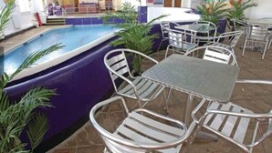 An indoor pool area with metal chairs and tables, surrounded by potted plants. - The Long Barn for Families, Pets & Workers (Penzance)