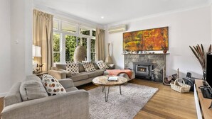 Un salon avec un canapé, une table basse, une cheminée et un grand tableau.