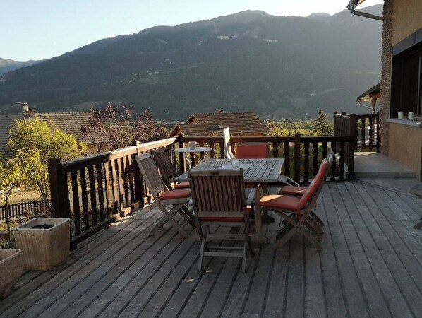 A wooden deck with a table and chairs, overlooking a mountainous landscape. - Laika's Chalet (Saint-Pons)