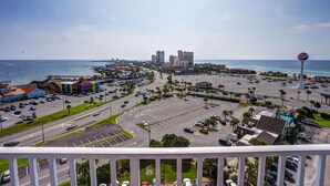 Paesaggio urbano con un'ampia area di parcheggio, un'imponente torre d'acqua e vista sull'oceano.