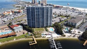 Vista aerea di una città costiera con un grande hotel, un porto turistico e una spiaggia.