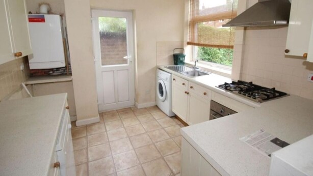 A compact kitchen with a washing machine, a sink, and a stove. - Inviting 5-bed House in Stockport Bramhall (Stockport)