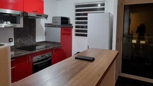 Una cuina compacta amb armaris vermells, un microones i un frigorífic.