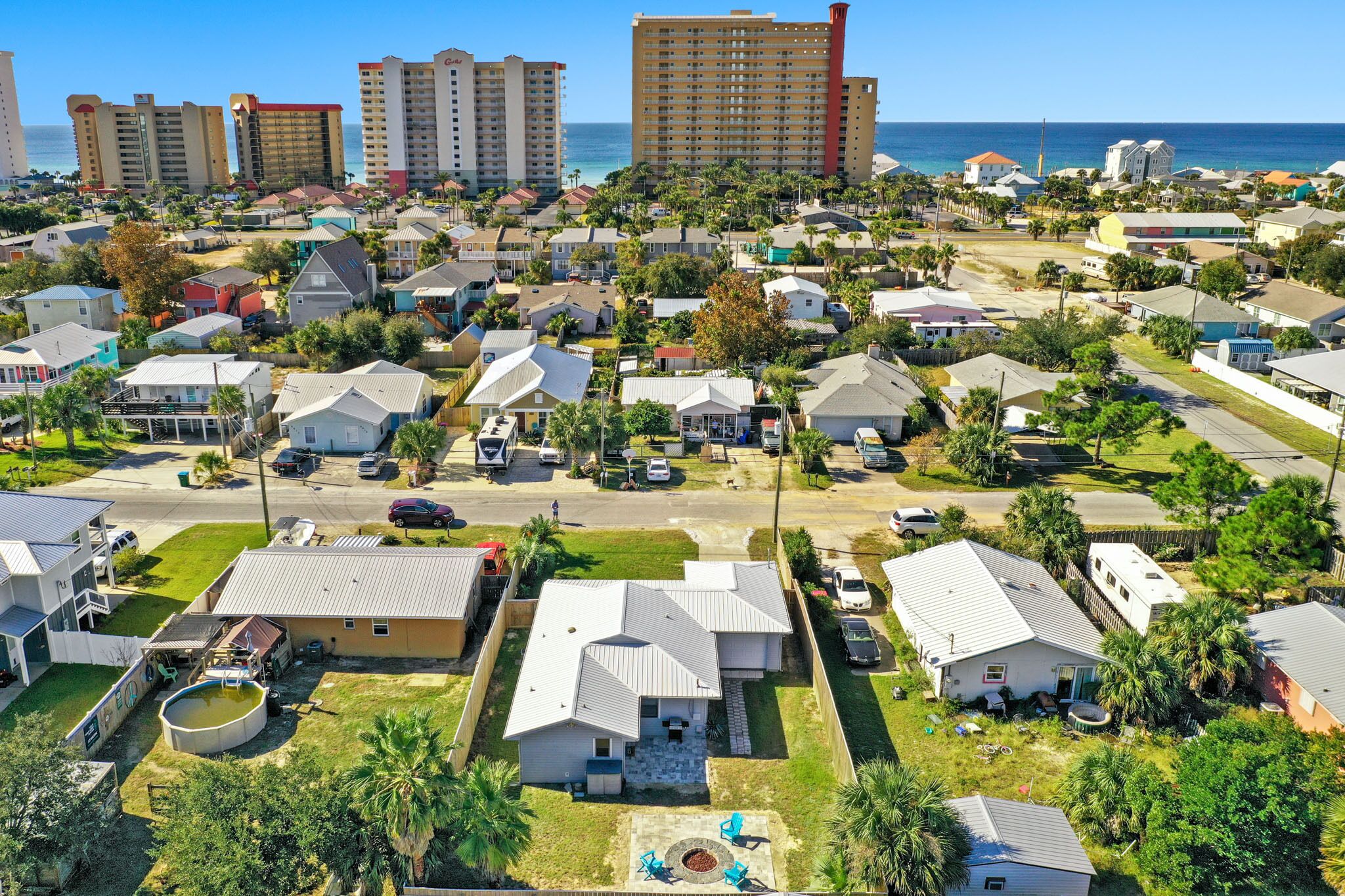 A residential area with single-family homes, a small pool, and a clear view of the ocean.