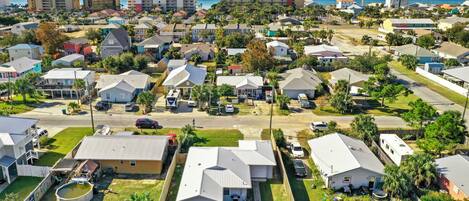 A residential area with single-family homes, a small pool, and a clear view of the ocean.