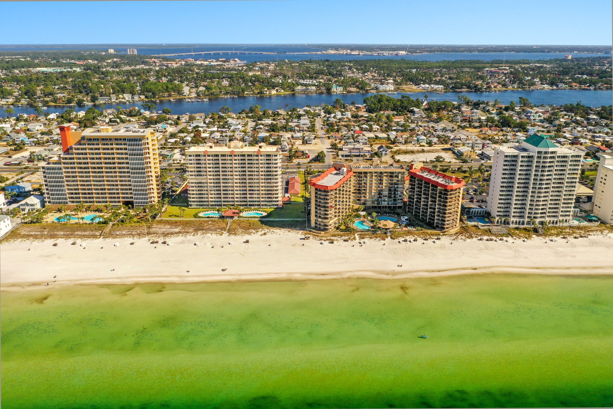 Ein Küstenort mit mehreren Hochhäusern, einem Sandstrand und einer Marina.