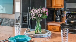 A dining table with a vase of flowers, blue plates, and clear glasses.