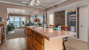 A spacious kitchen with a central island, a ceiling fan, and a view to a balcony.