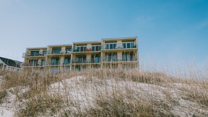A beachfront hotel with multiple balconies and a sandy foreground.