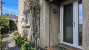 A house with a stone exterior, a sliding glass door, and a small porch area with a green mat. - Terrace, Garden, Apartment 80m², mountain view, wifi, office (Bagnères-de-Bigorre)