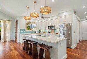 A modern kitchen with a central island, stainless steel appliances, and pendant lighting.