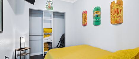 Un dormitorio con una cama, un armario y una estantería con objetos.