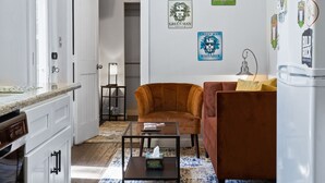 A compact living space with a kitchenette, a ceiling fan, a brown sofa, and a coffee table. - Container Home w/ a Fenced Yard (Hendersonville)