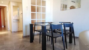 Habitació d'hotel amb zona de menjador que inclou una taula i caires, un mirall gran a la paret i un vas groc al sòl.