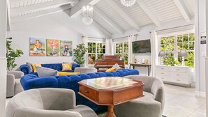 Un salón amplio con un sofá azul, una mesa de centro de madera y un piano.