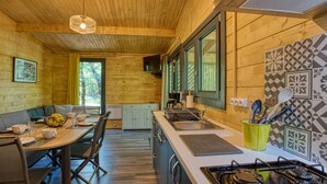 L’intérieur d’un chalet en bois comprend un coin repas, une cuisine et de grandes fenêtres.